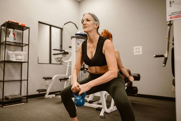A man is lifting a barbell over his head in a gym.