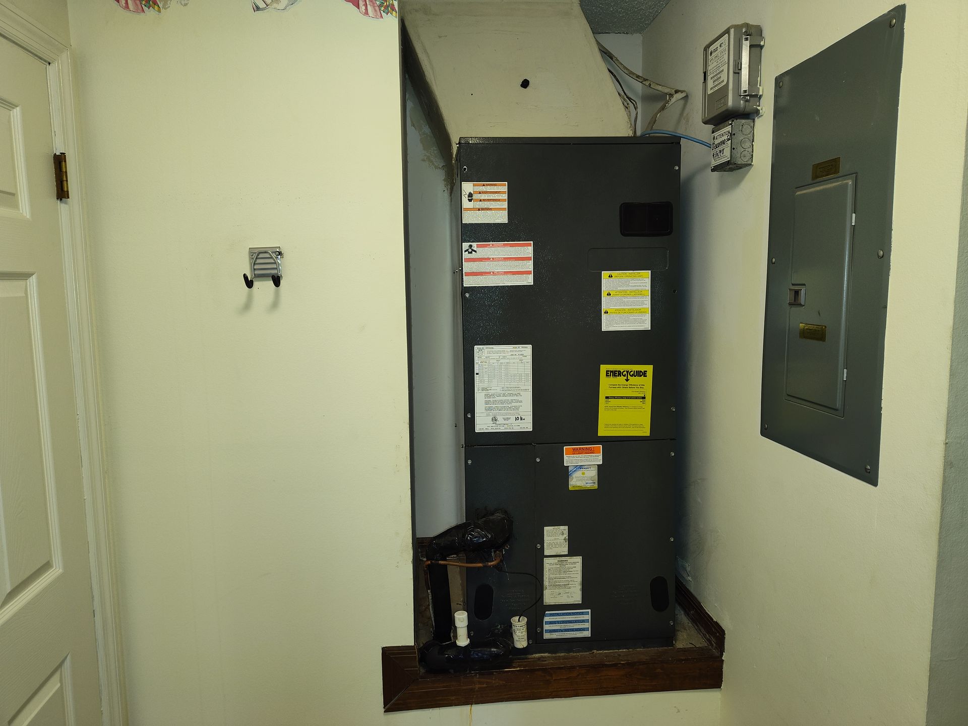 an air conditioner is sitting in a corner of a room next to a door .