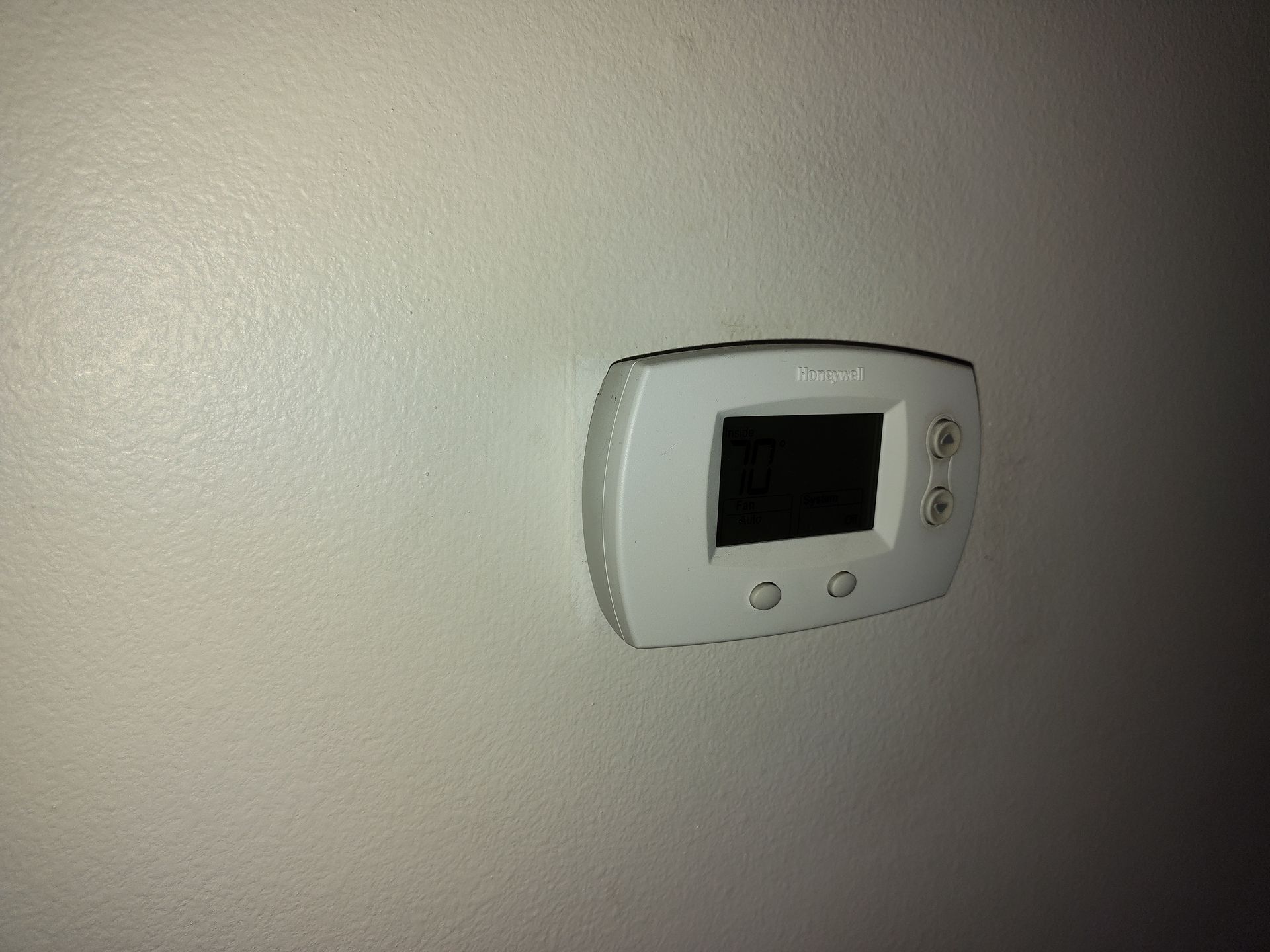 a white thermostat is mounted on a white wall