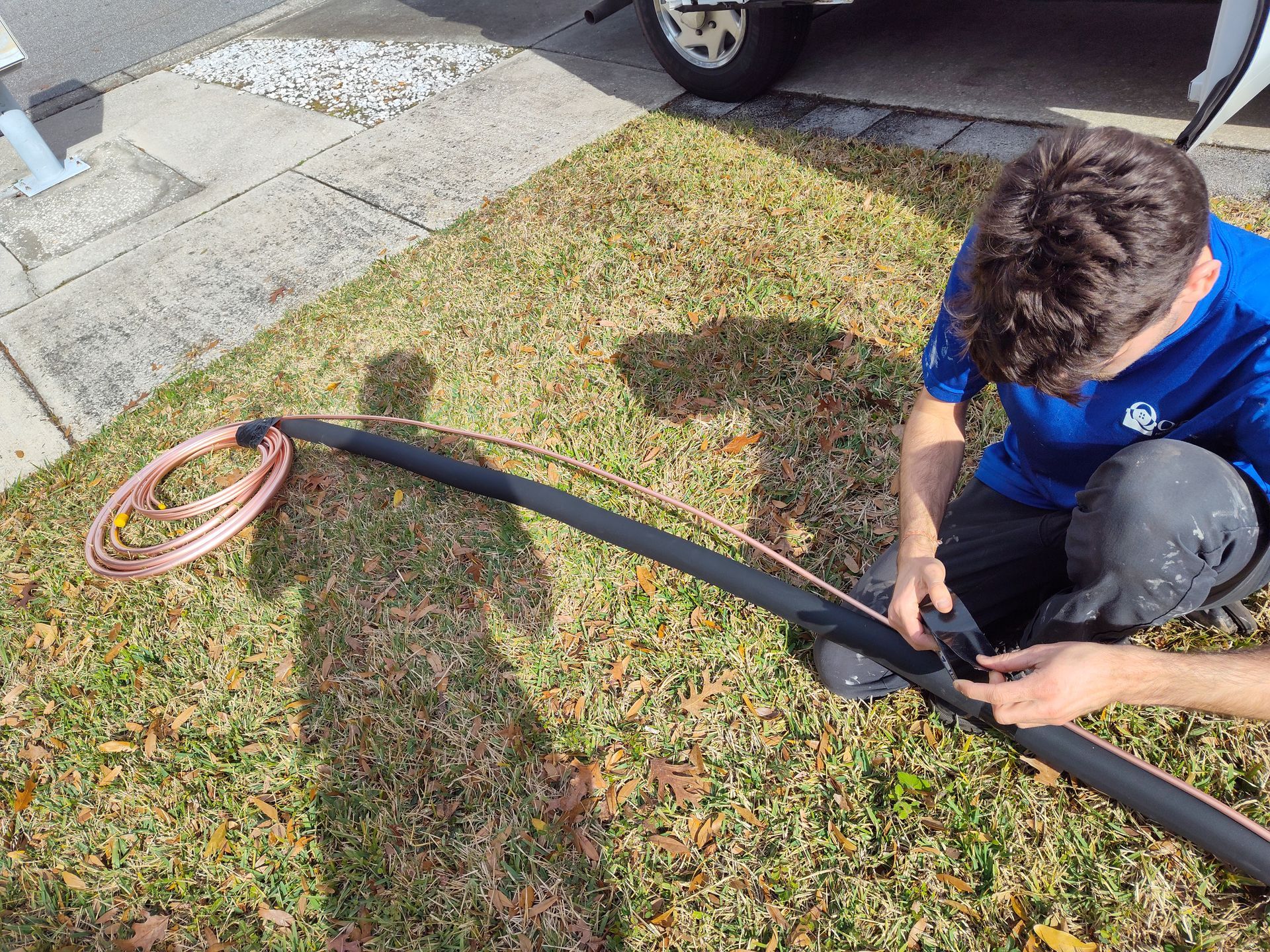 a man in a blue shirt is sitting on the grass with a hose .