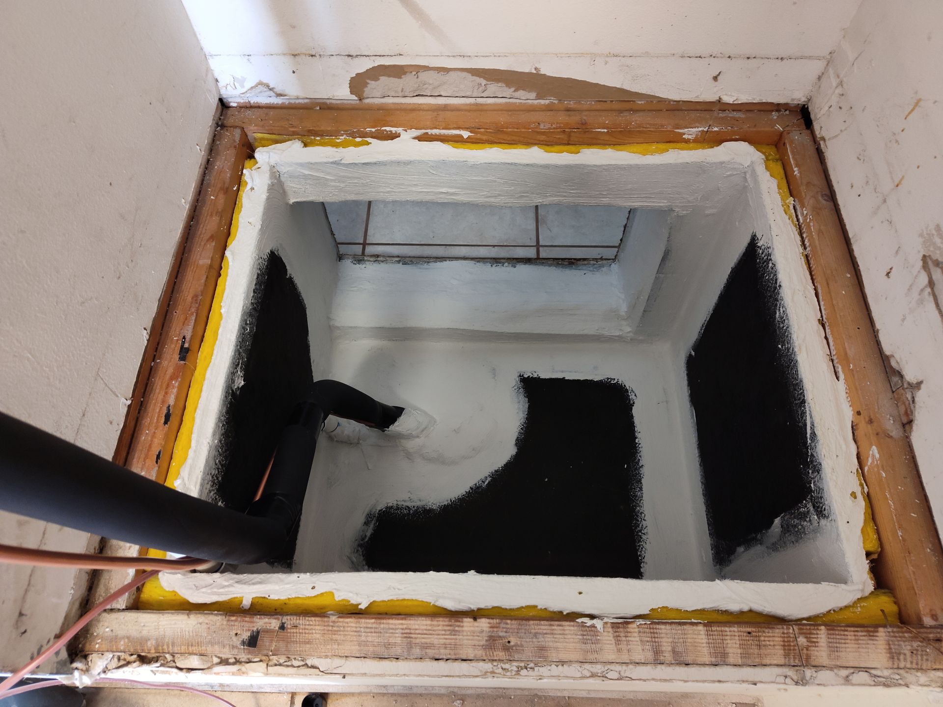 a hole in the floor of a room with a pipe coming out of it