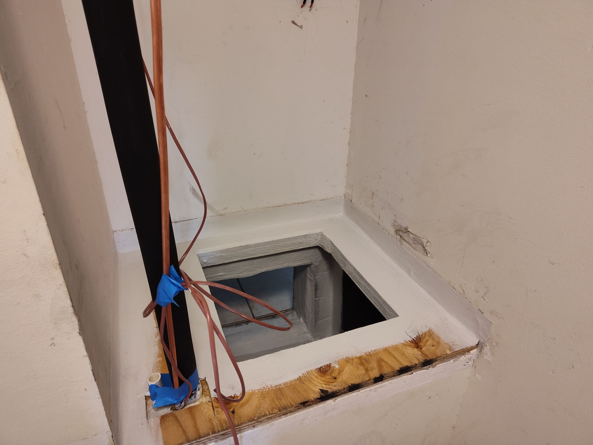 a hole in the floor of a room with a pipe coming out of it