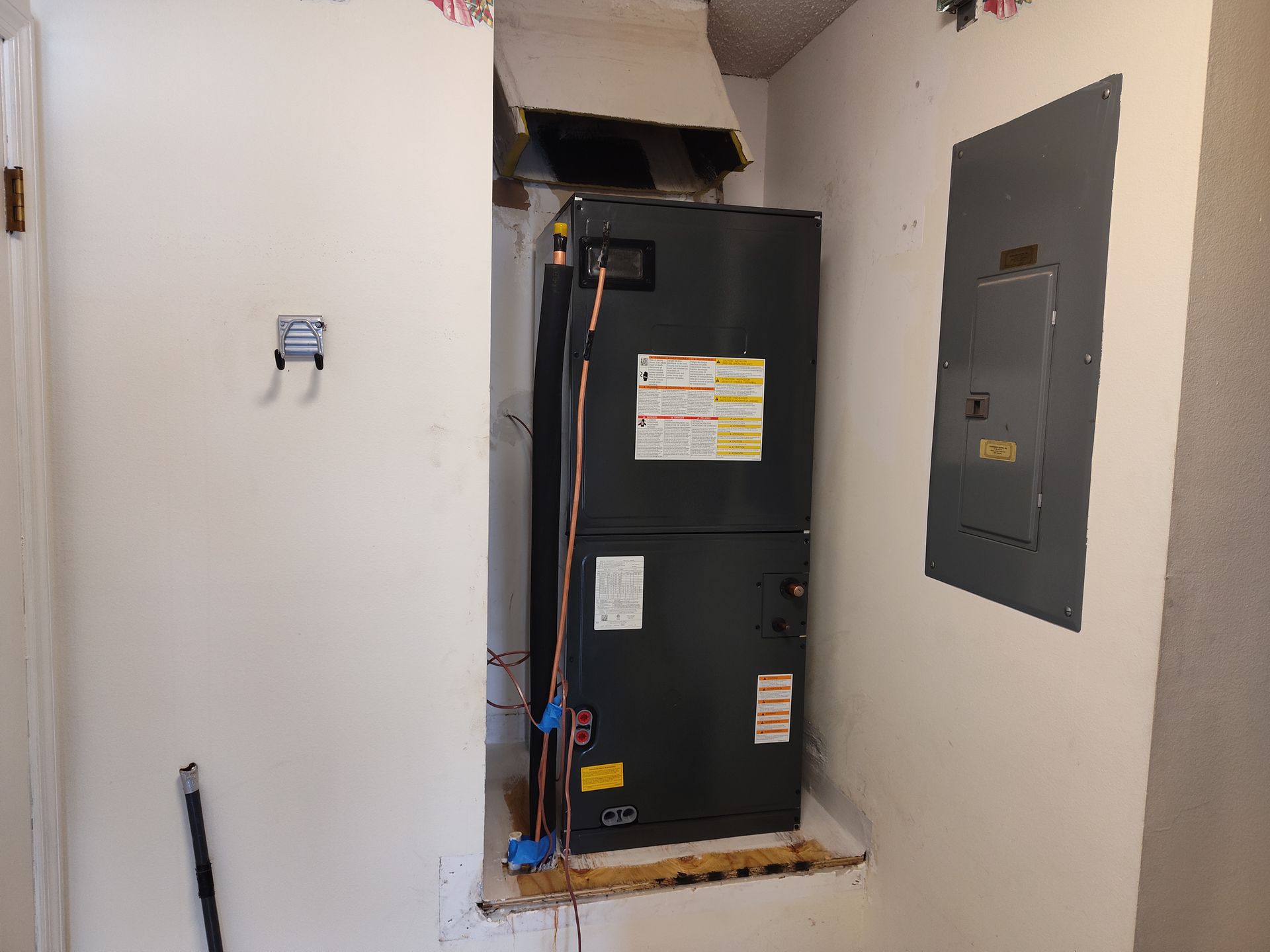 a black air conditioner is sitting in a corner of a room next to a wall .