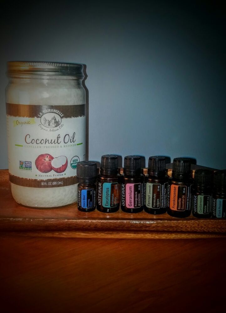 A Jar of Coconut Oil and Bottles of Essential Oils Are on a Wooden Shelf