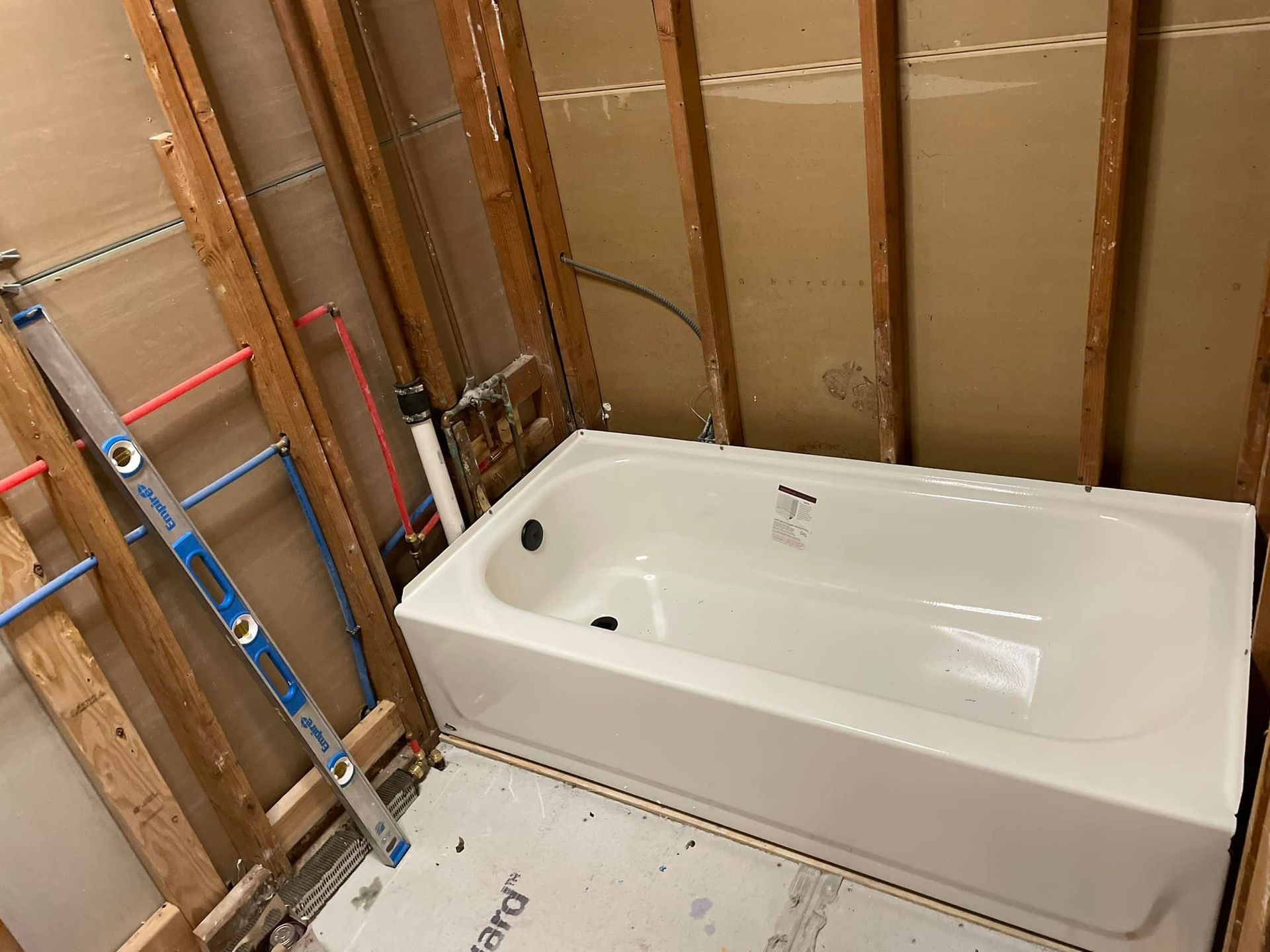 Bathtub installed in a bathroom under renovation. Plumbing and studs are visible.