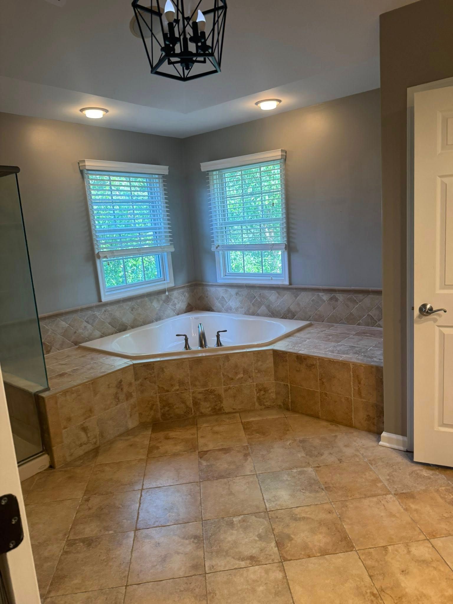 Bathroom with corner jacuzzi tub, windows, tile, and neutral walls.