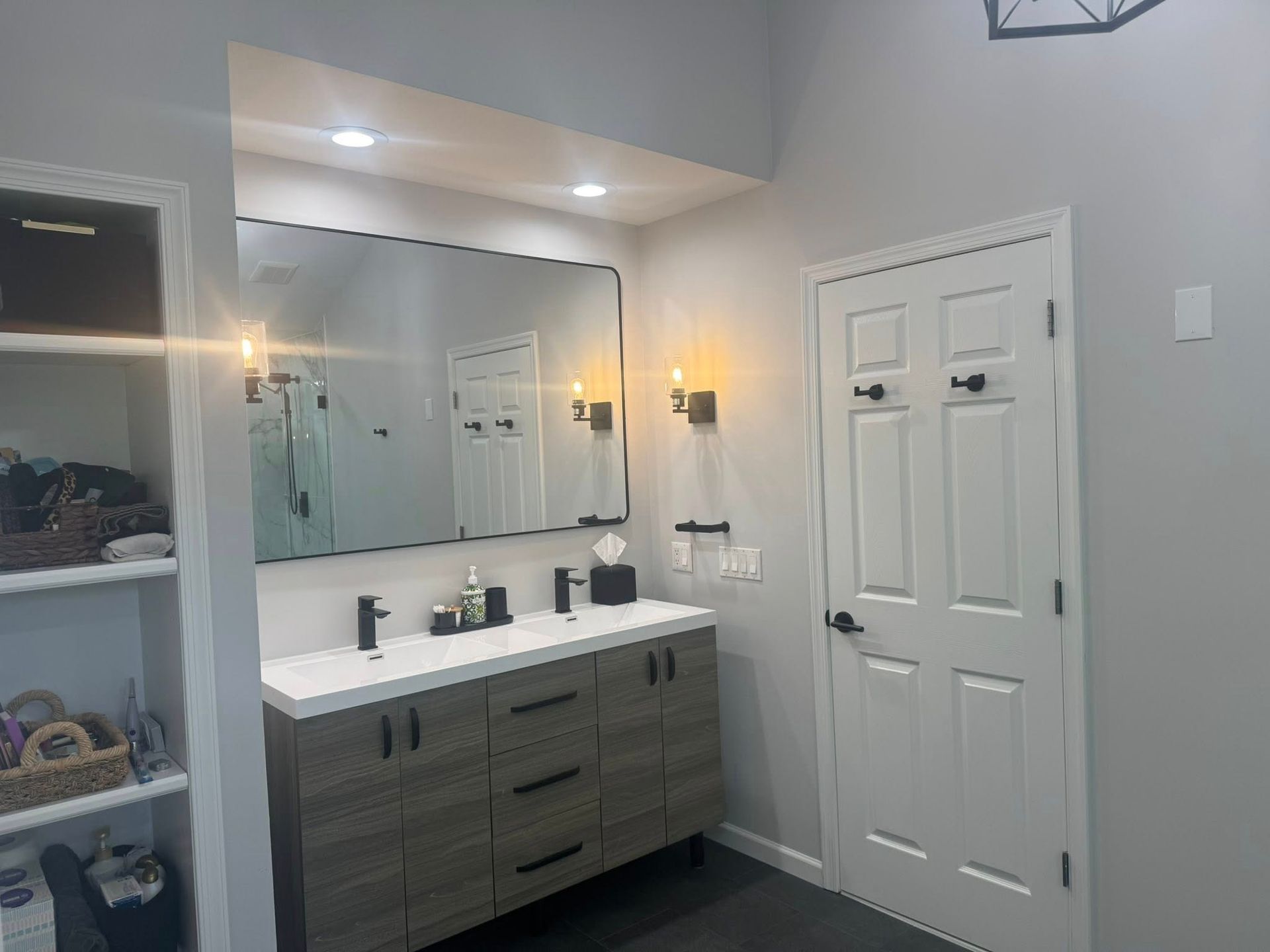 Bathroom with white herringbone tile, glass shower door, black hardware, and recessed shelves.