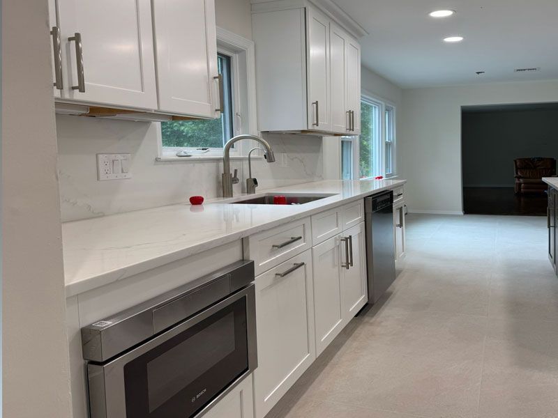 White kitchen with stainless steel appliances, white cabinets, and light countertops.