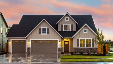 A large house with two garage doors and a sunset in the background.