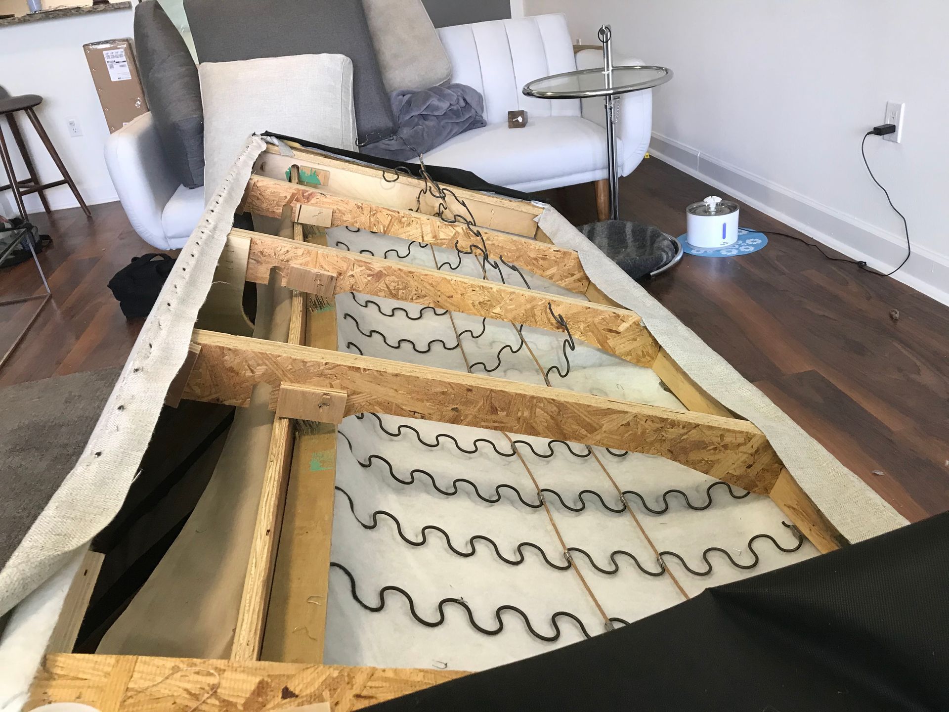 A couch is being dismantled in a living room.