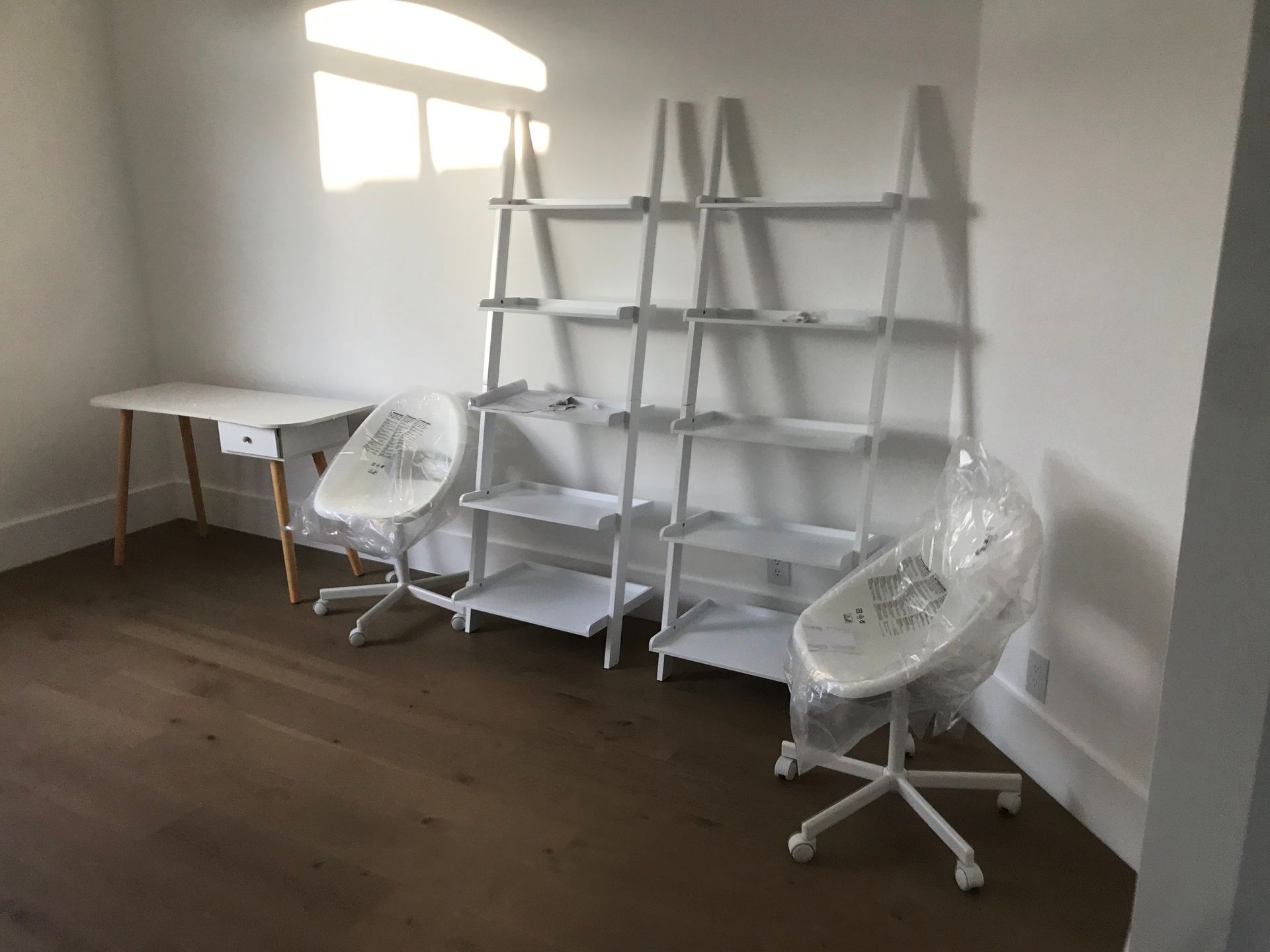 A room with a desk , chairs , shelves and a window.