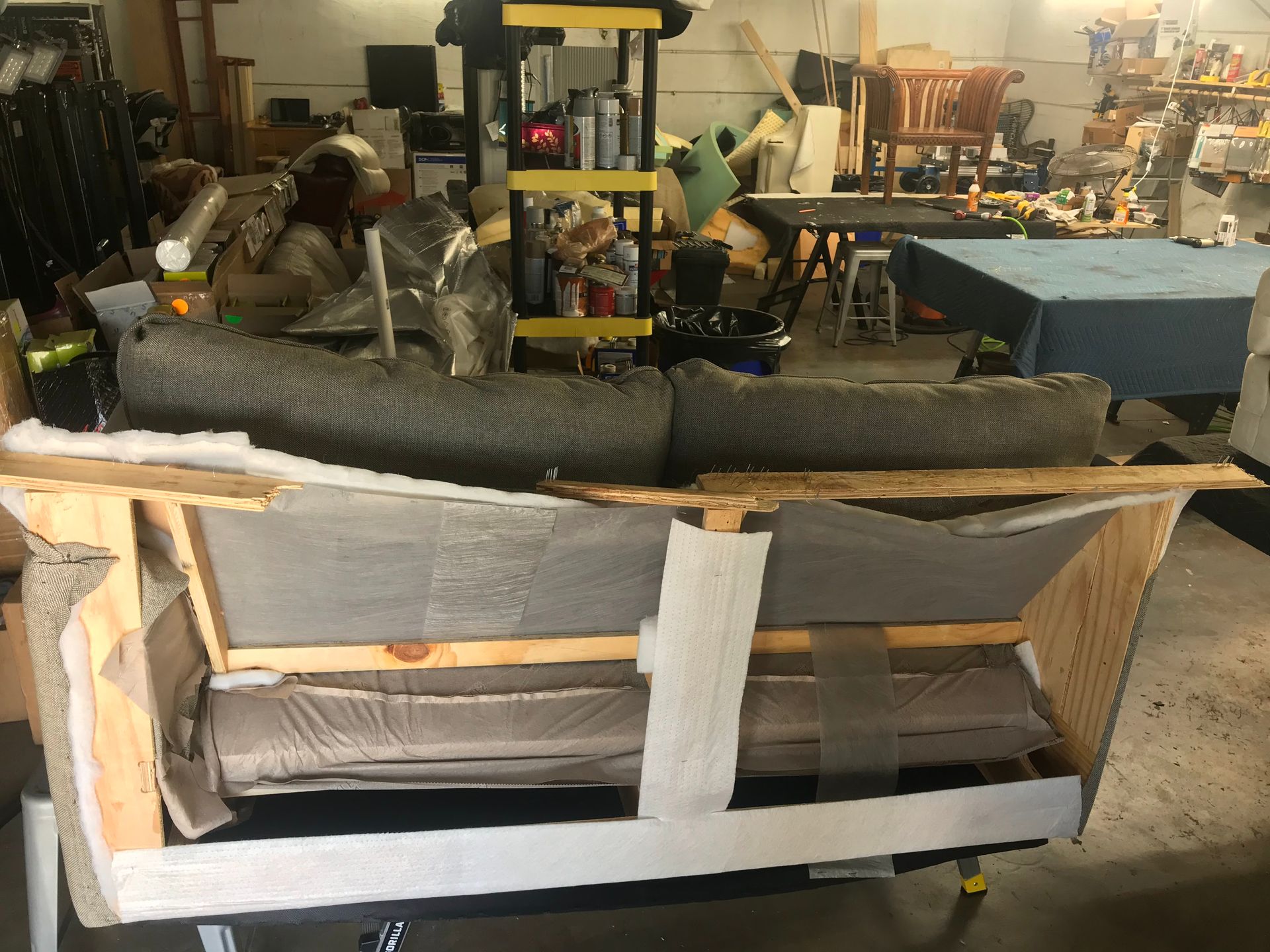 A couch is sitting in a wooden box in a garage.