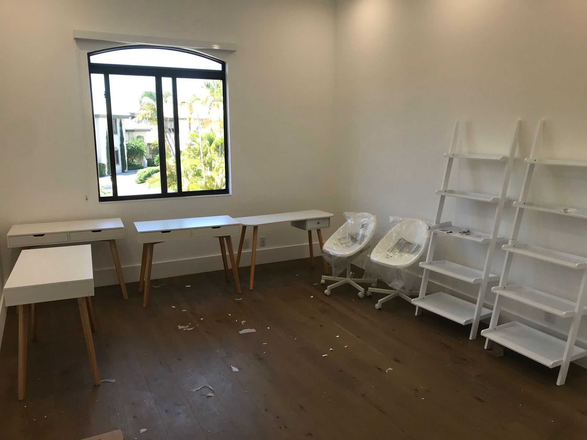 A room with a lot of white furniture and a window.
