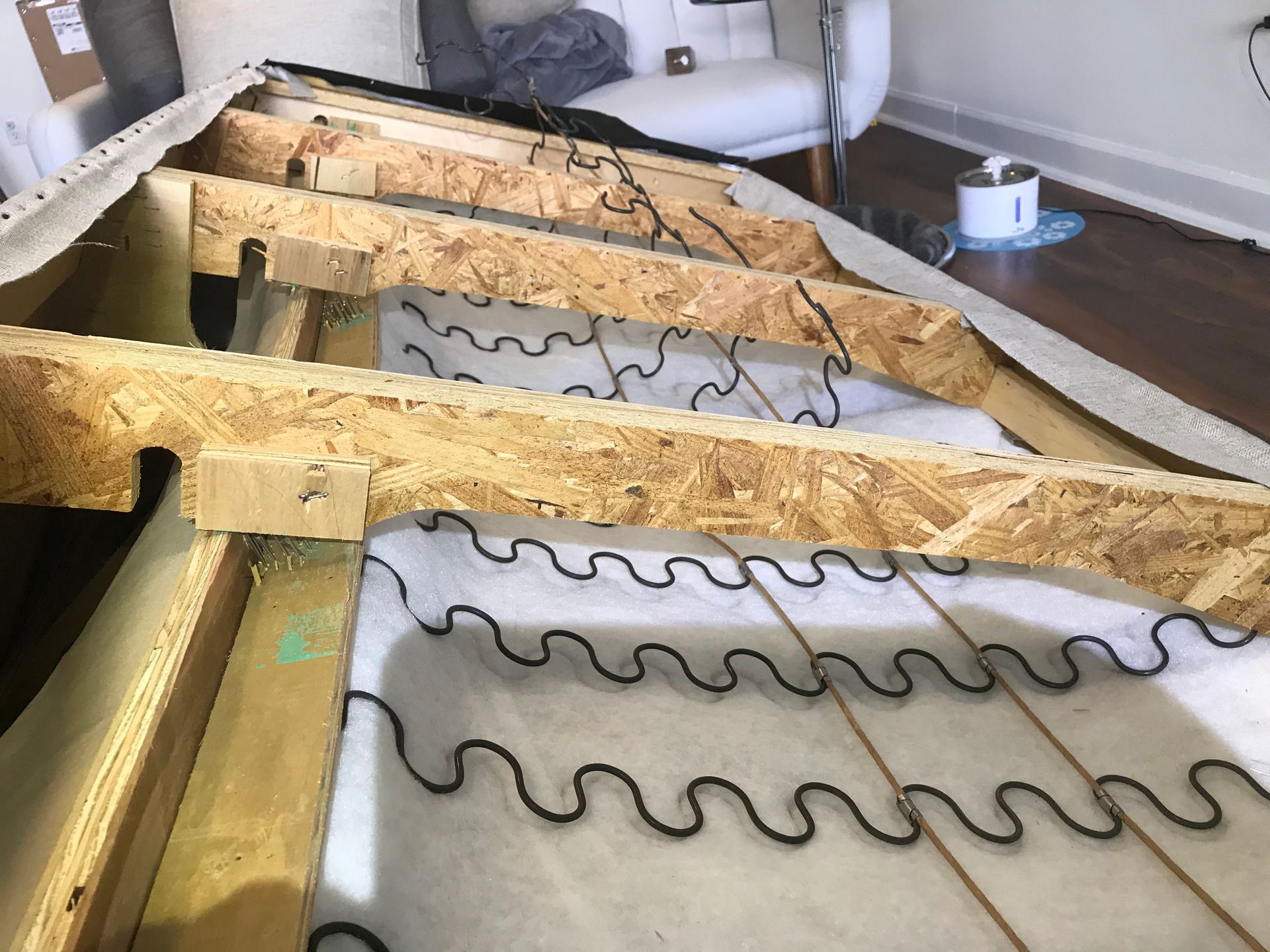 A wooden frame of a couch is sitting on a wooden floor in a living room.