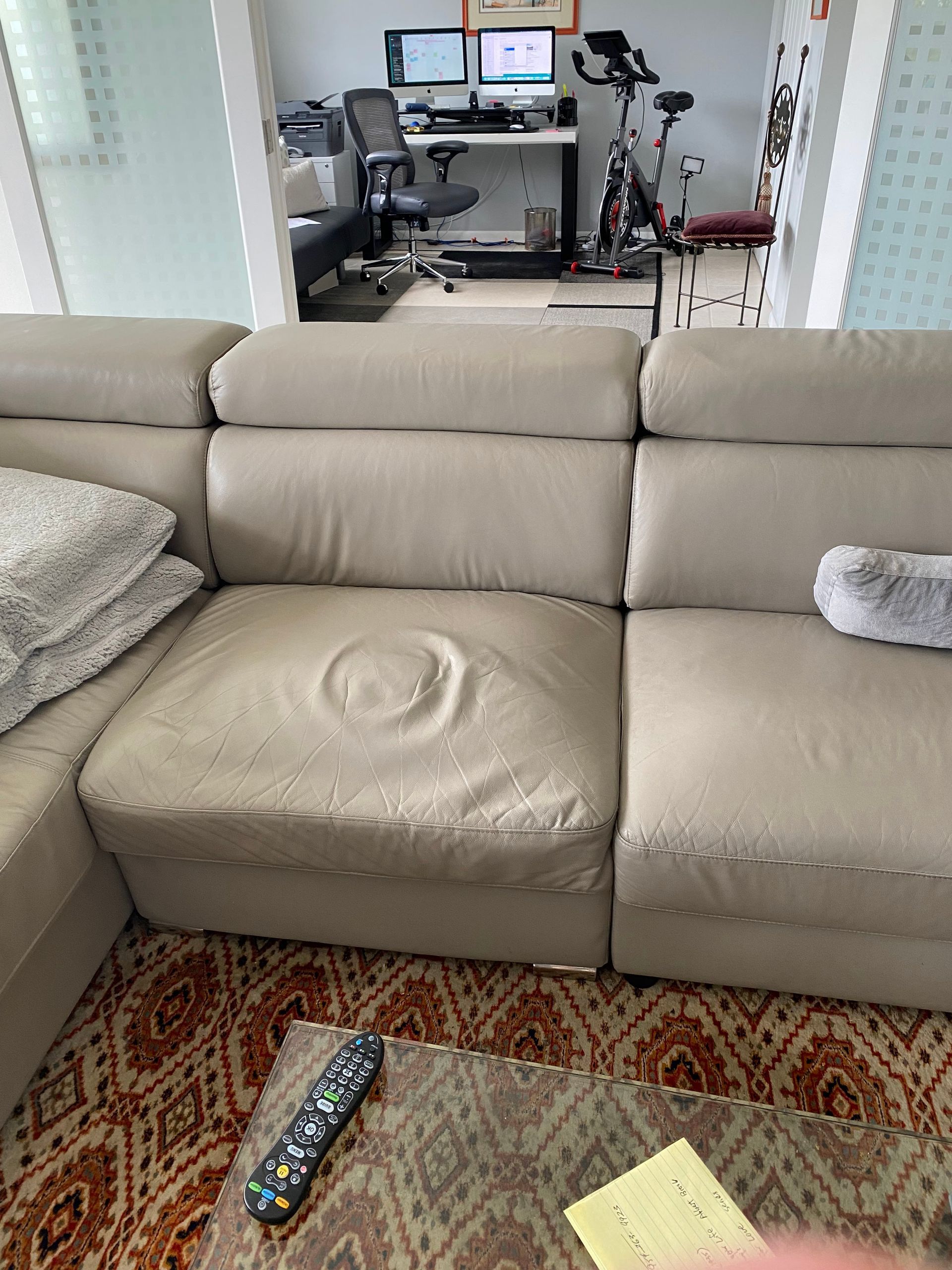 A couch is sitting in a living room next to a table with a remote control on it.