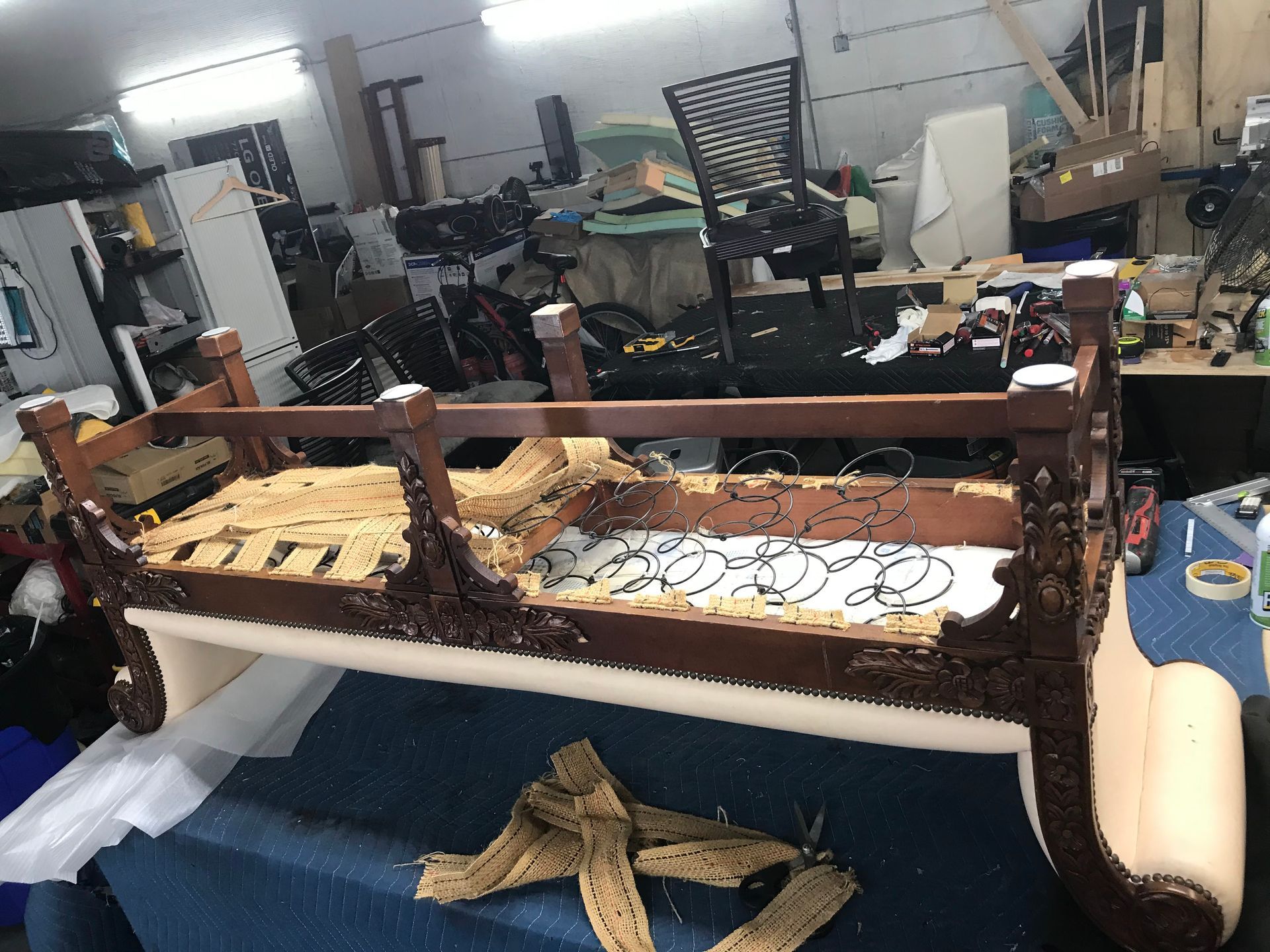 A wooden couch is being repaired in a workshop.