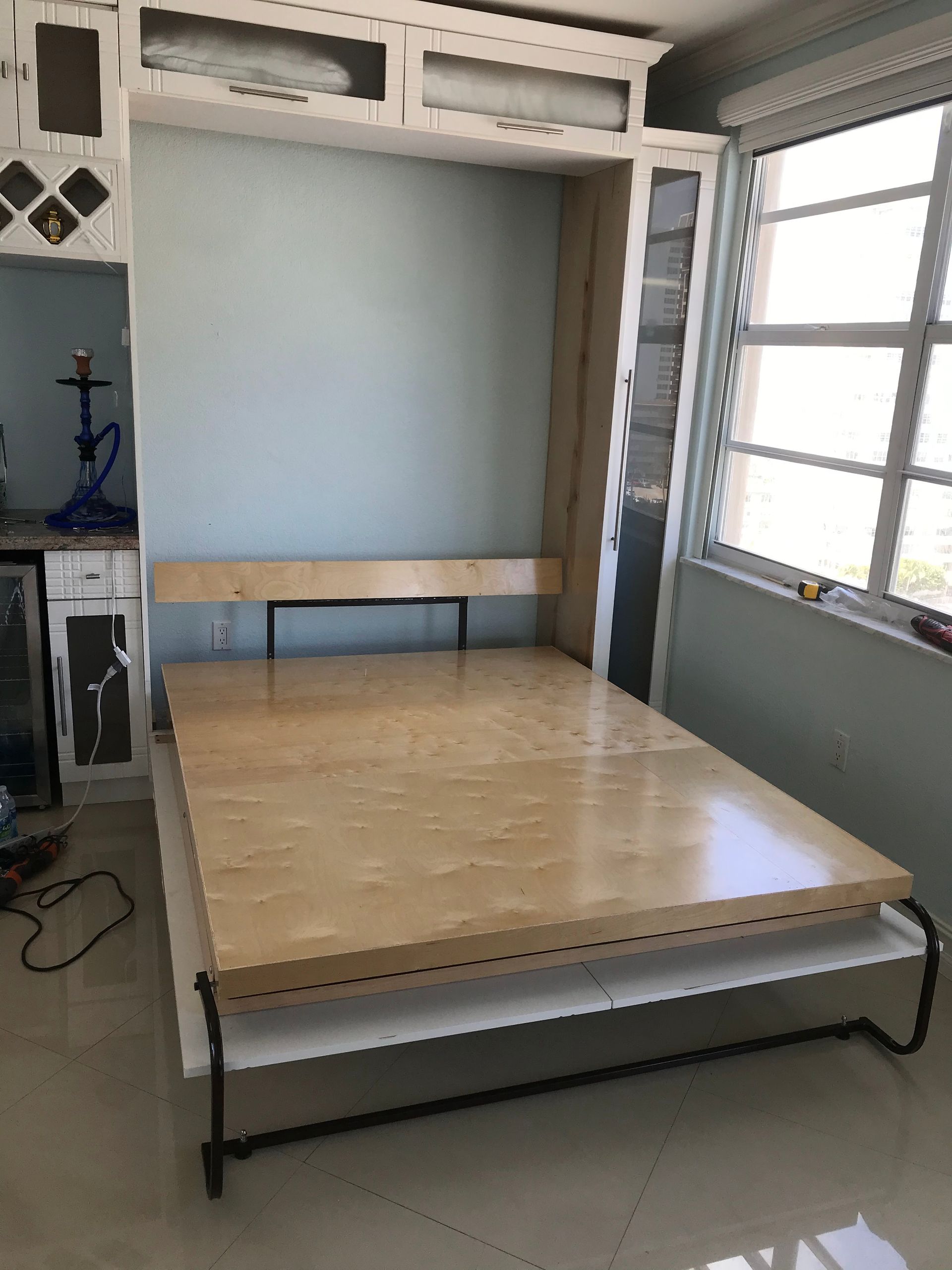 A wooden bed is sitting in a room next to a window.