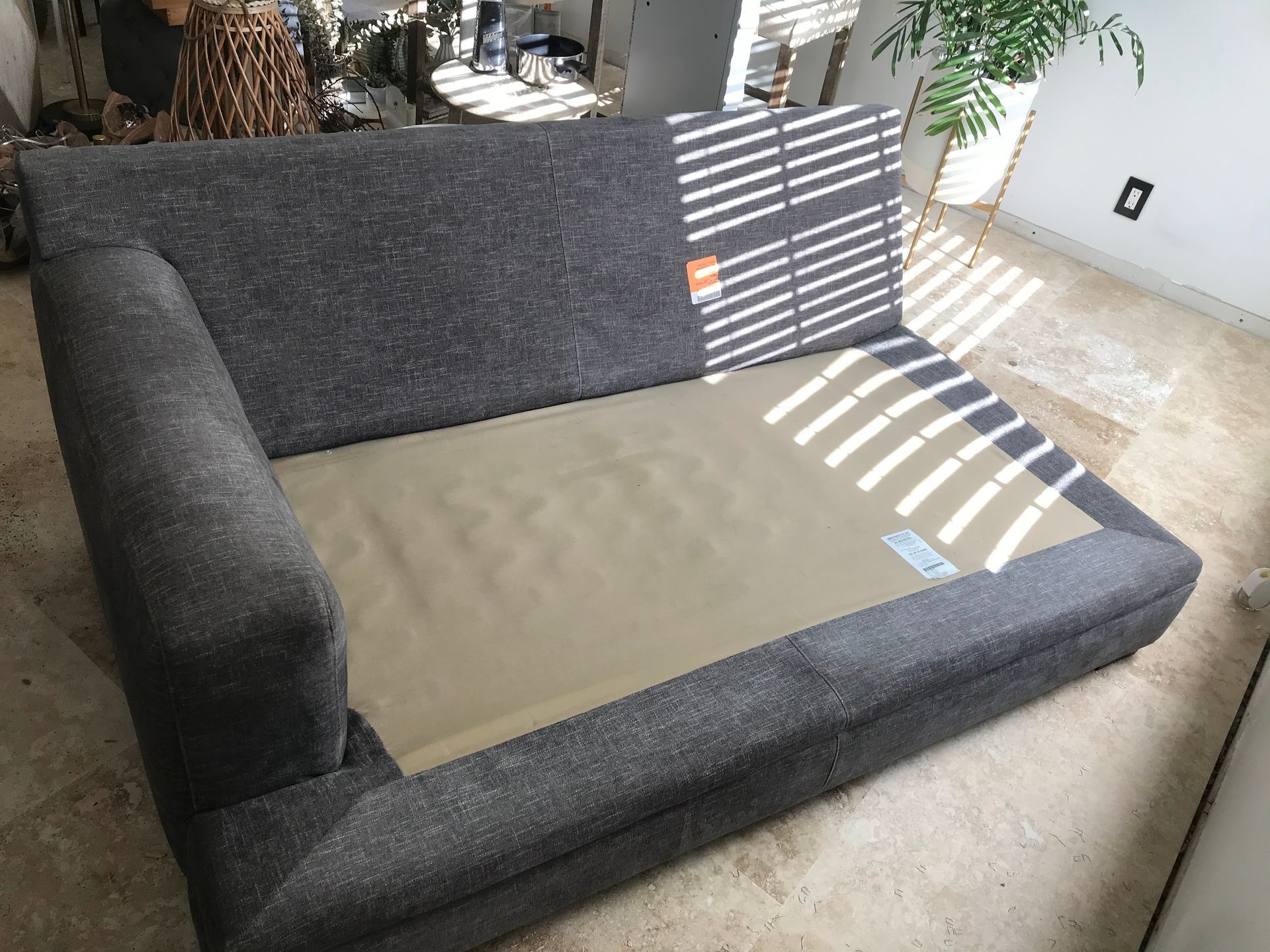 A grey couch is sitting on a tiled floor in a living room.