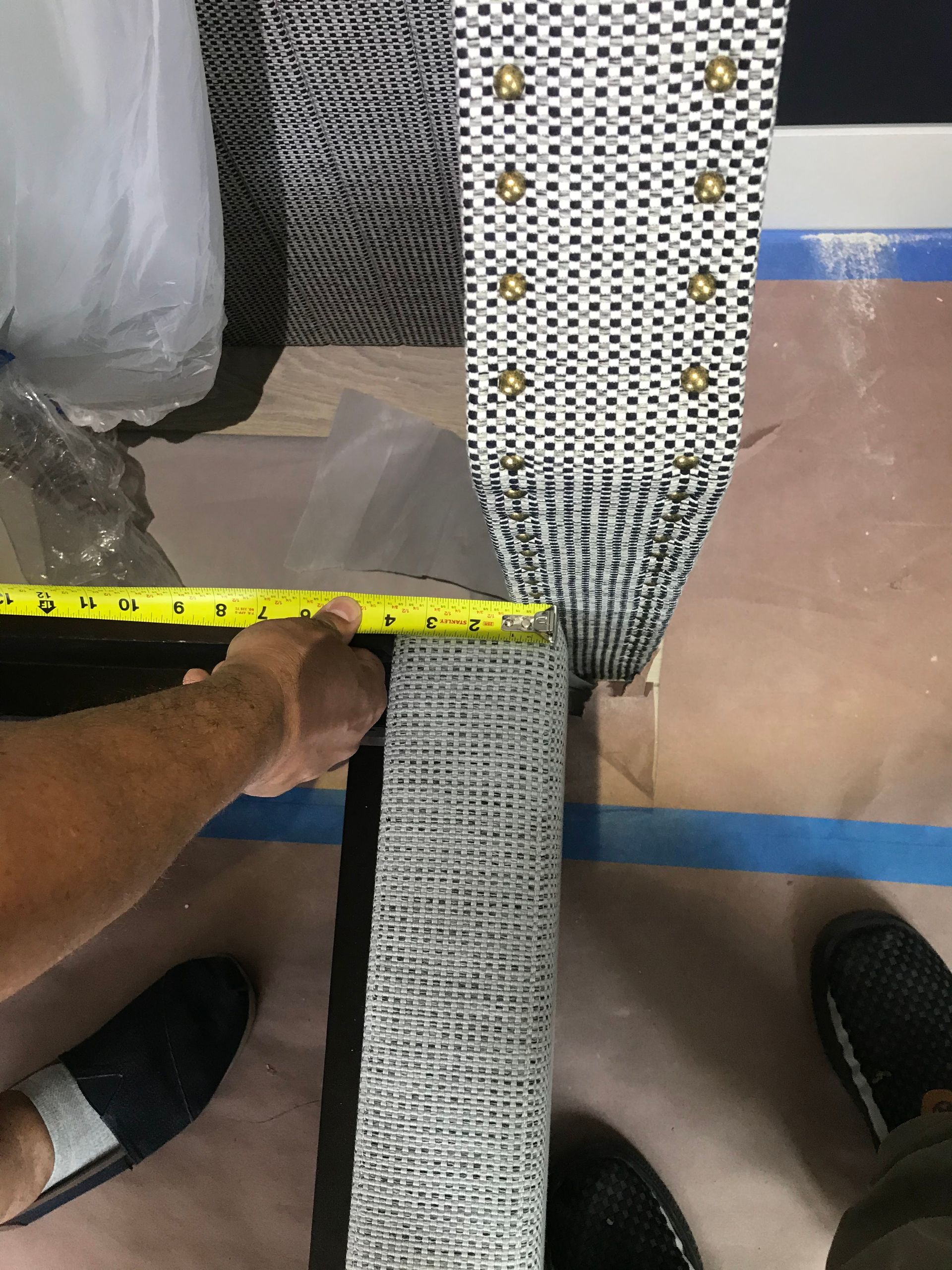 A person is measuring a piece of wood with a tape measure.