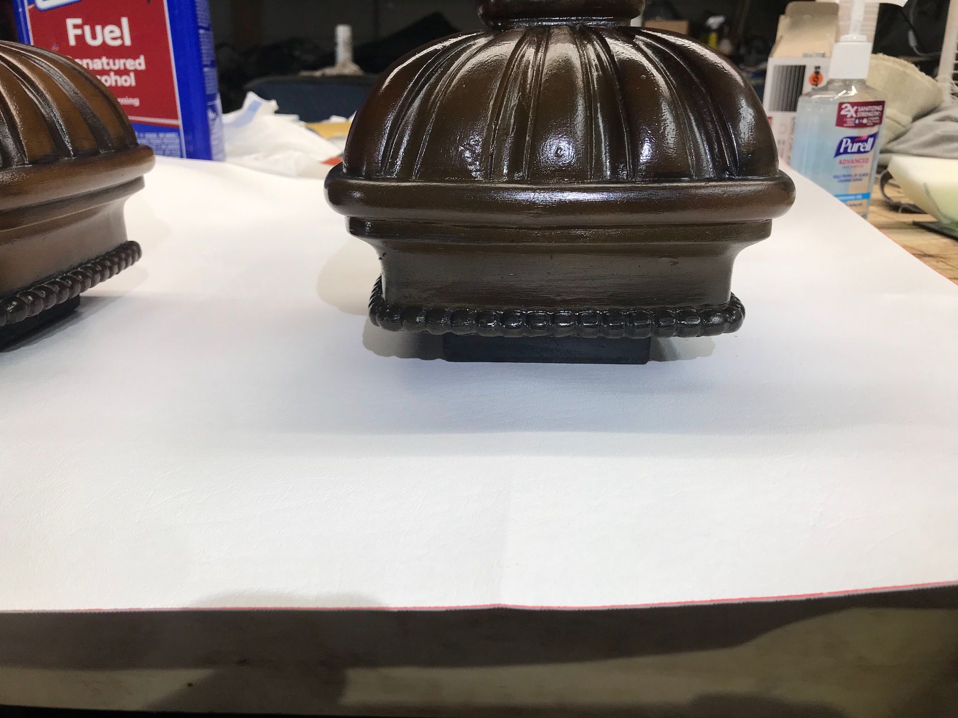 A bottle of fuel sits on a table next to a brown object