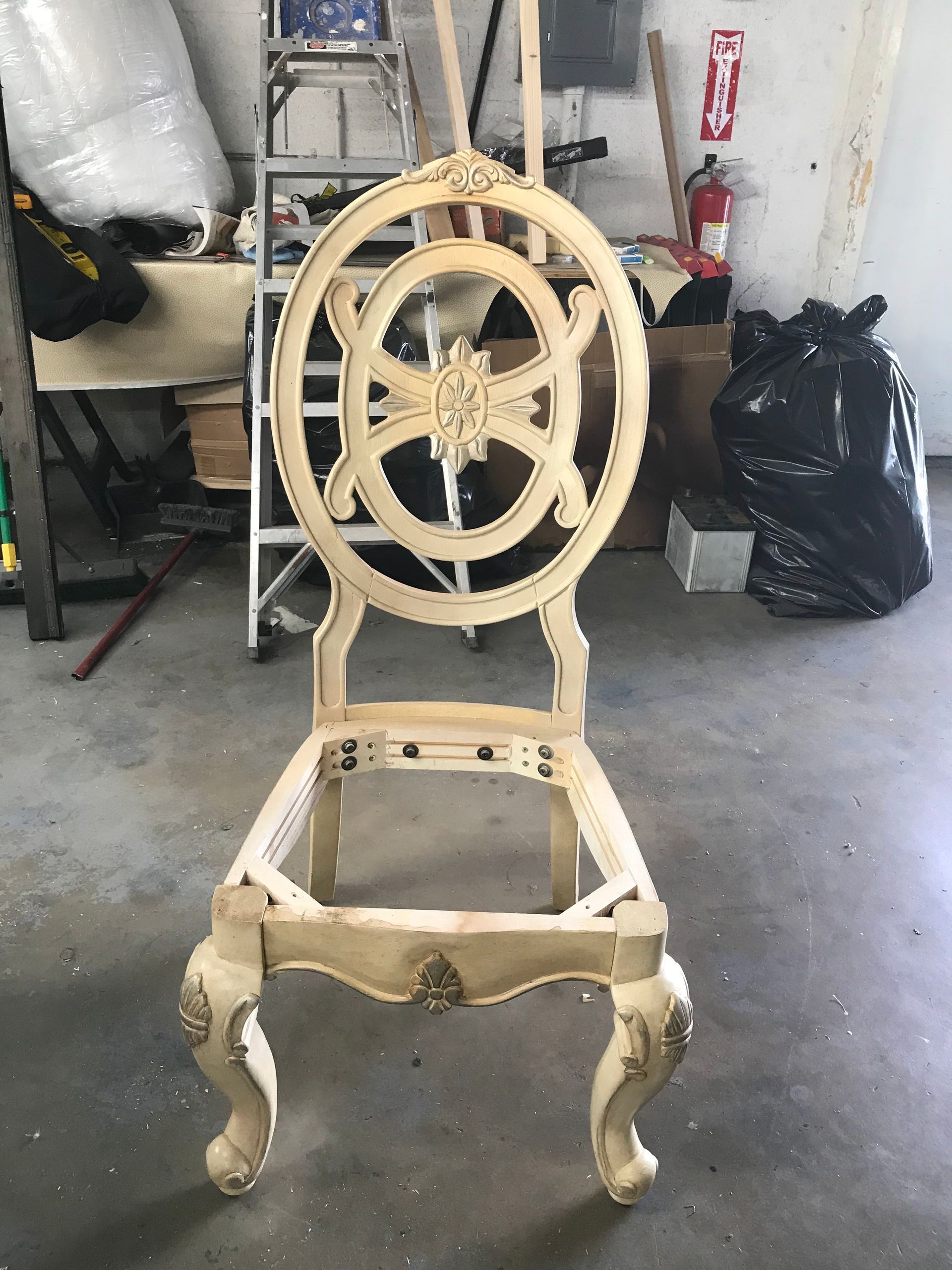 A wooden chair is sitting on the floor in a garage.