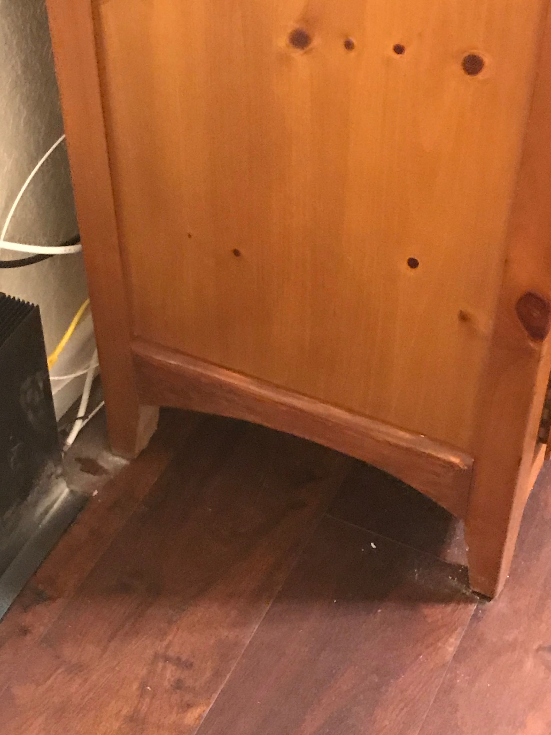 A wooden cabinet is sitting on a wooden floor.