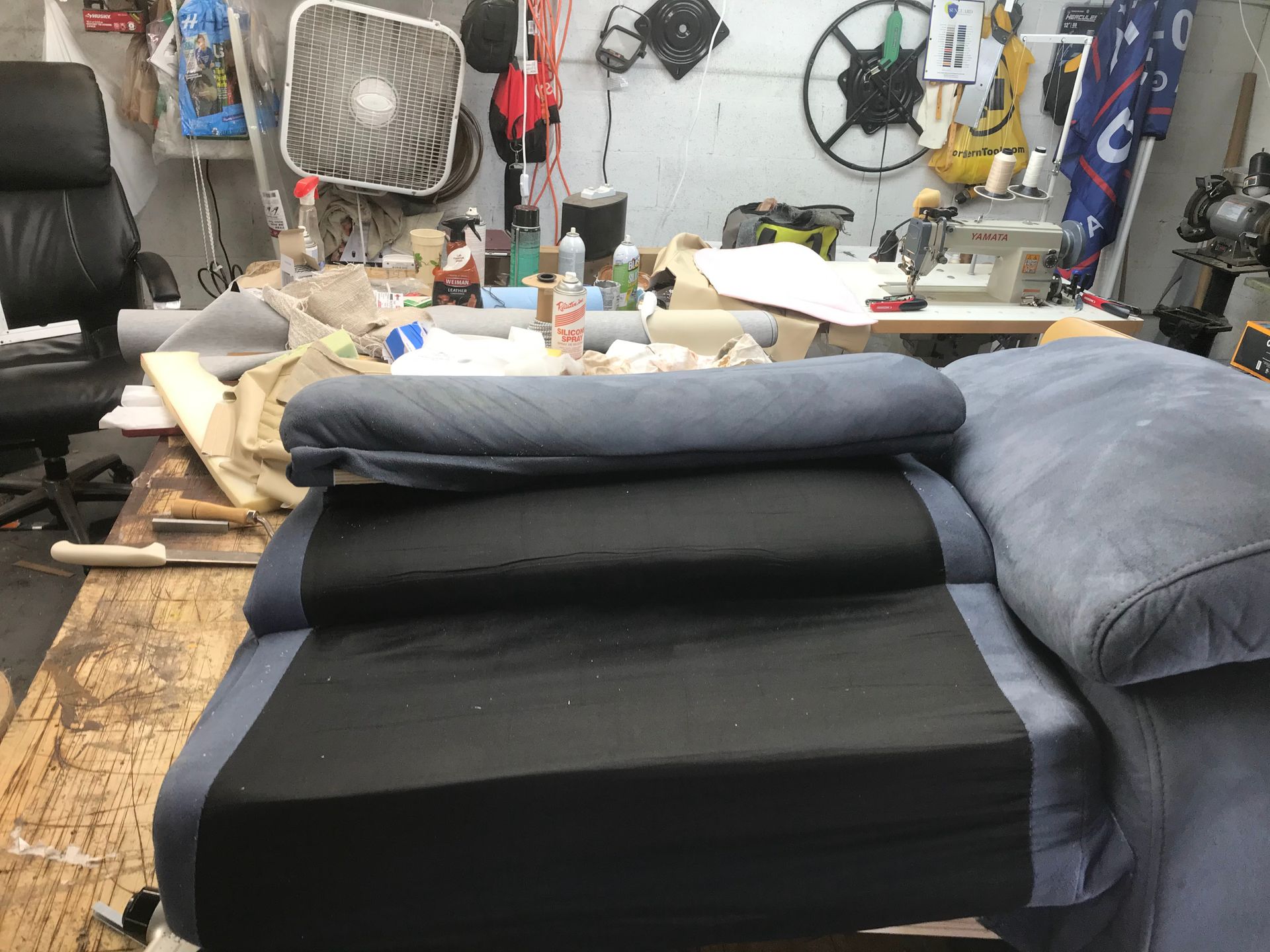 A blue couch is sitting on a table in a messy room.