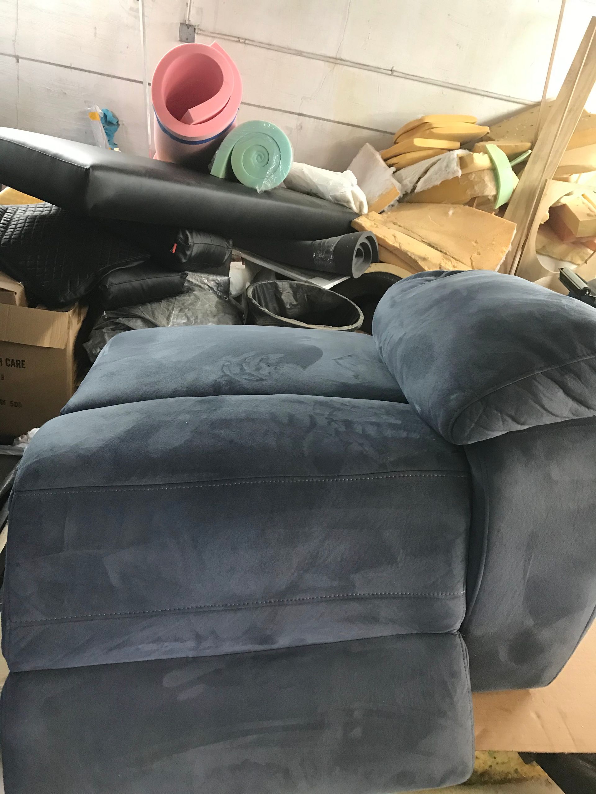 A blue chair is sitting on top of a pile of cardboard boxes.