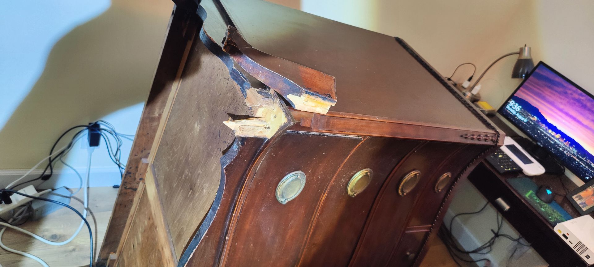 A computer monitor is sitting on a desk next to a wooden dresser.