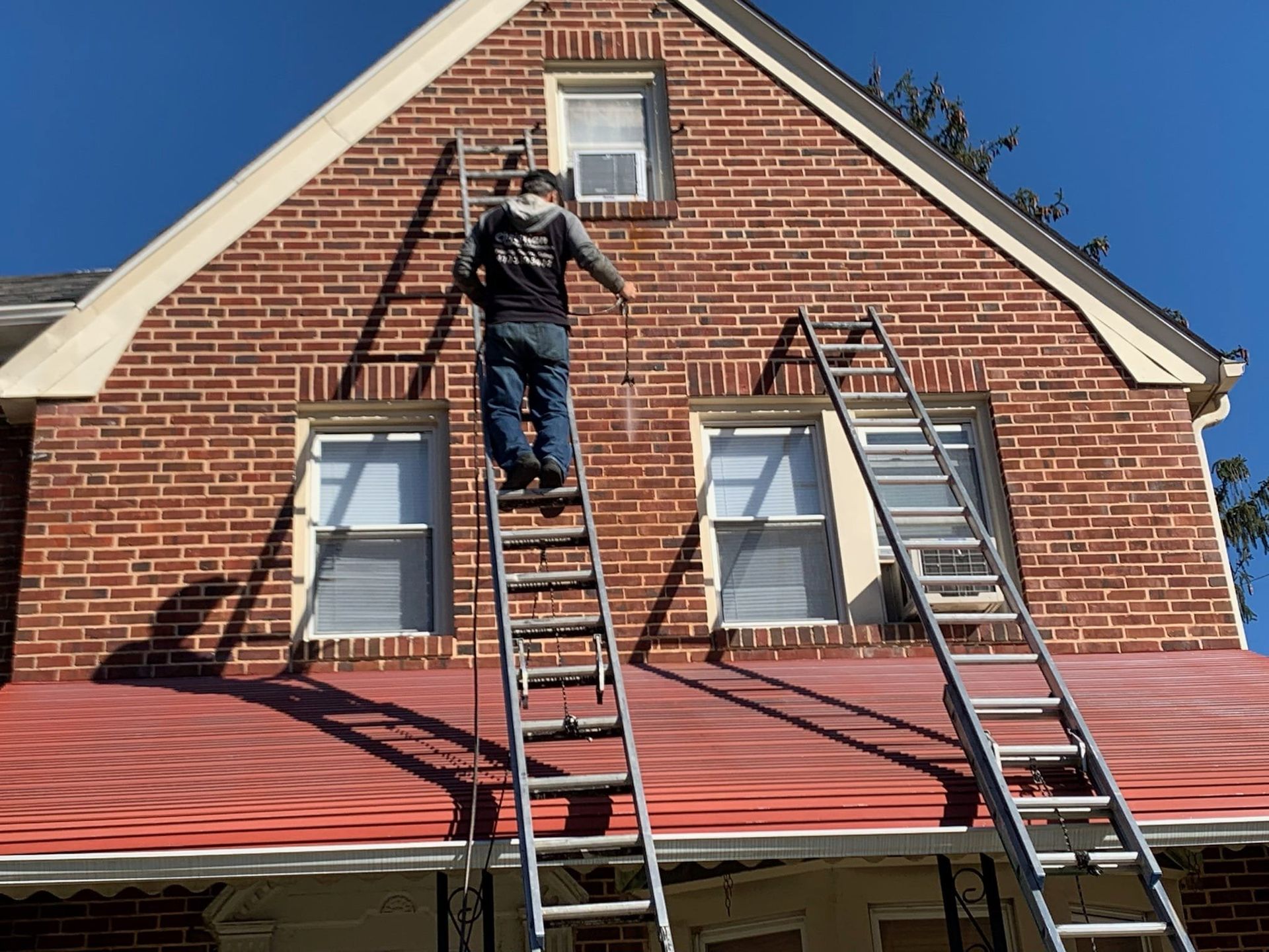 A man is standing on a ladder on top of a brick building.