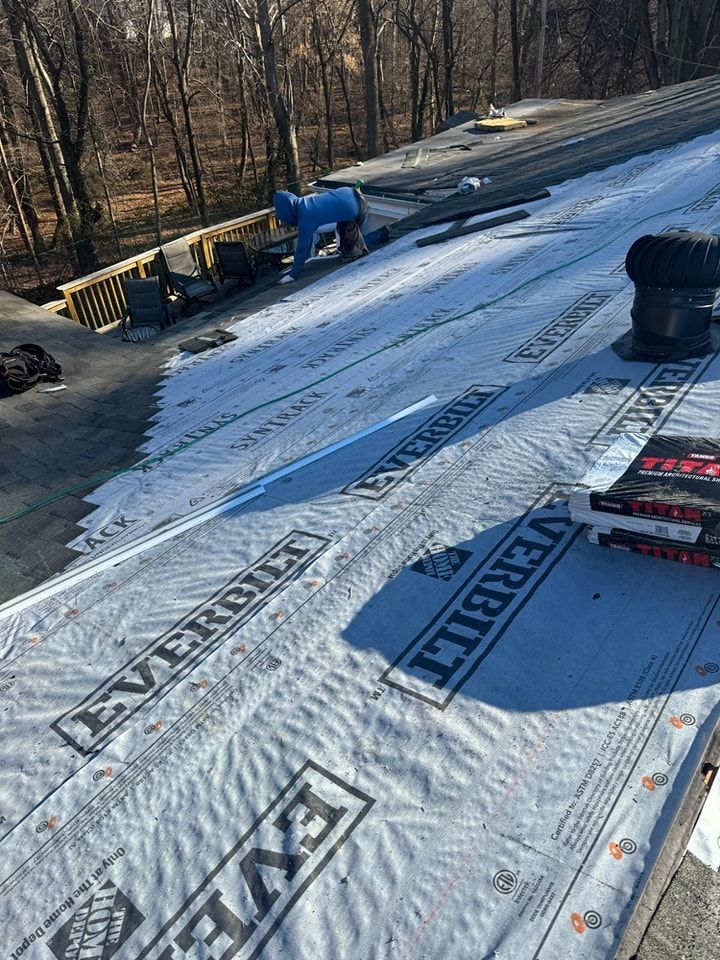 A roof with a lot of snow on it and trees in the background.