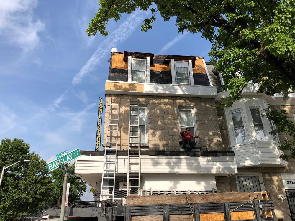 A man is sitting on a ladder on the side of a building.