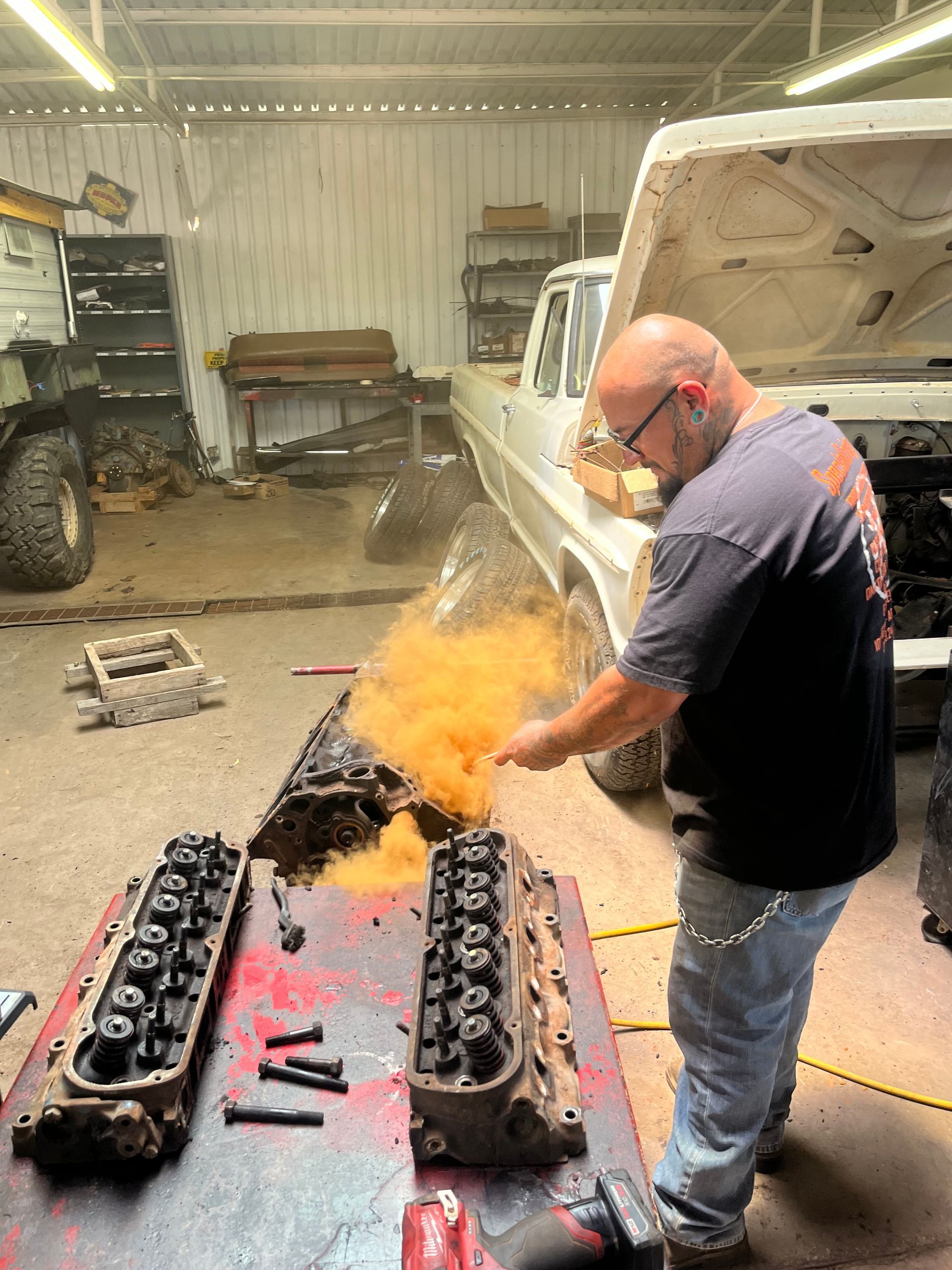 A man is working on a truck engine in a garage.