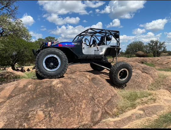 A jeep is sitting on top of a large rock.