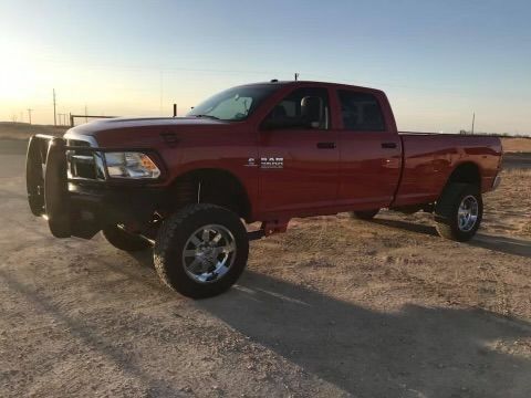 A red dodge ram truck is parked on a dirt road.