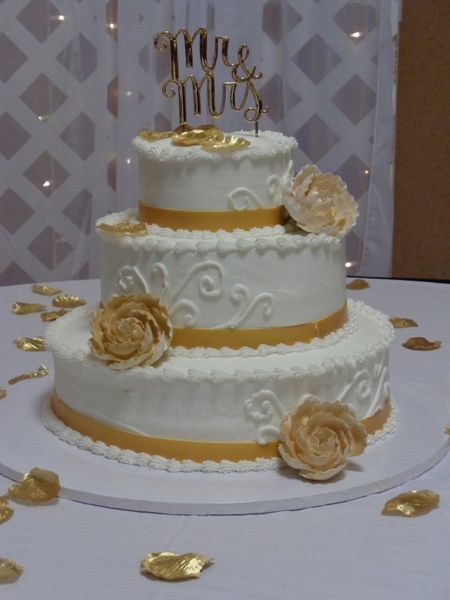 Three-tiered wedding cake, white frosting with gold accents, 