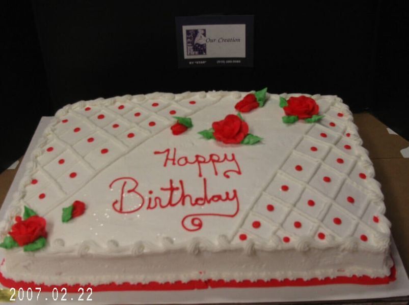 Rectangular birthday cake with white frosting, red polka dots and roses, and 