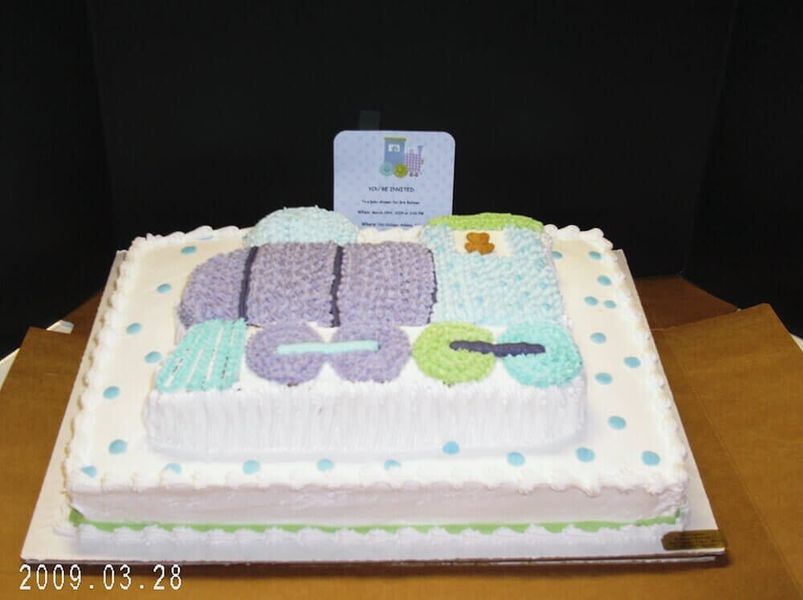 Cake decorated as a train, blue, purple, and green on white background with blue polka dots.