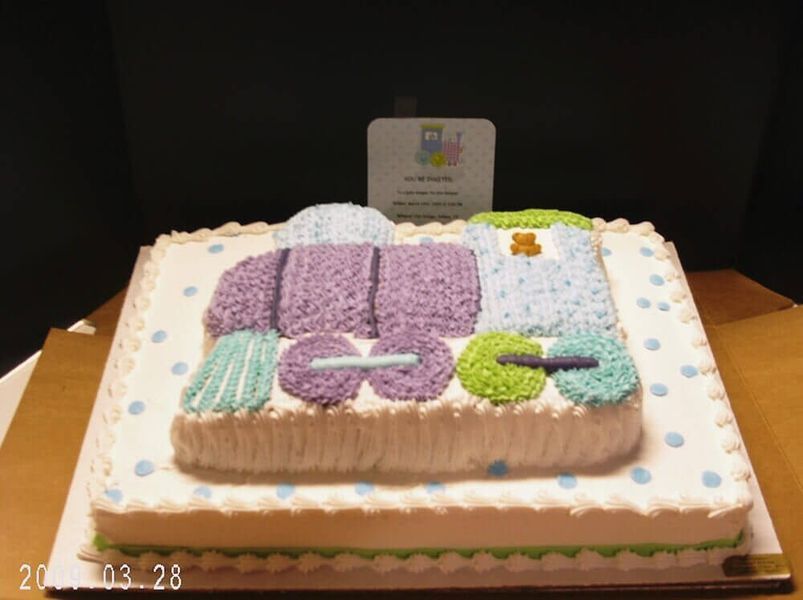 Train-shaped cake with purple, green, and blue icing, on a square cake with blue polka dots.