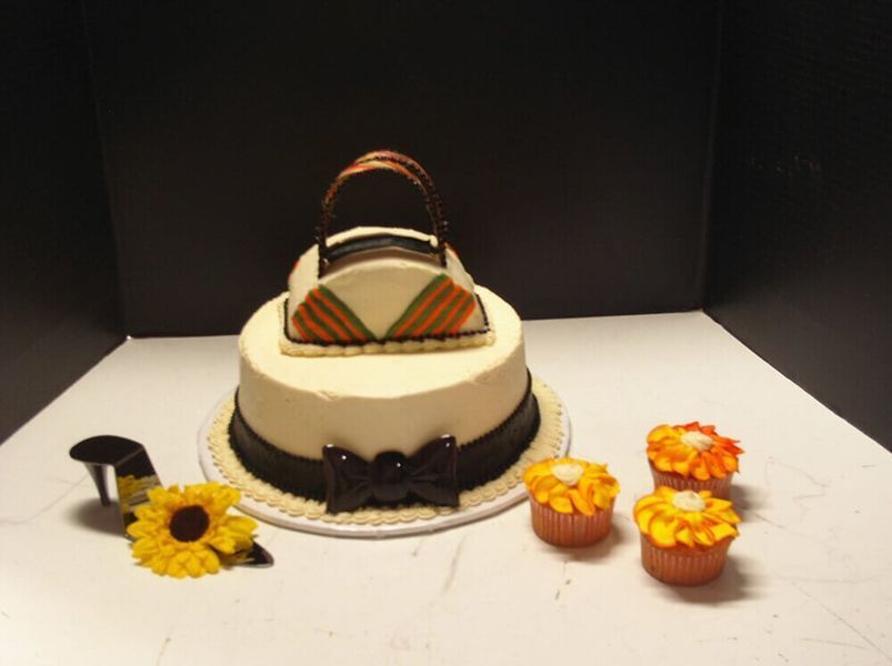 Cake decorated as a handbag, with cupcakes and a sunflower.