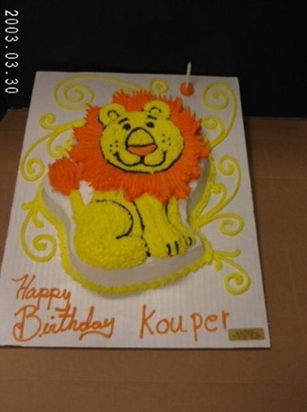 Lion-shaped cake with orange mane, yellow body, and 