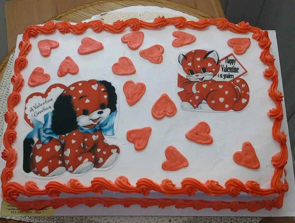 Valentine's Day cake with red hearts, a dog, and a cat, all with red polka dots. Orange frosting border.