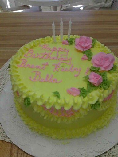 Yellow birthday cake with pink roses and candles. 