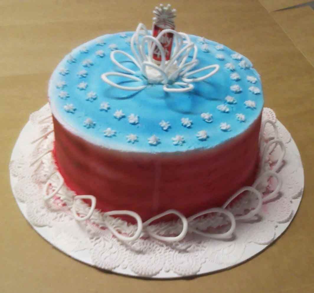 Cake with blue top, red sides, white floral decorations, and a silver topper on a white plate.