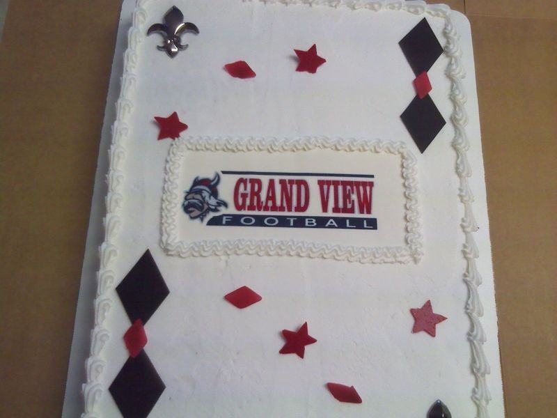 Cake decorated for Grand View Football, with team logo, fleur-de-lis, and card suit shapes in red and black.