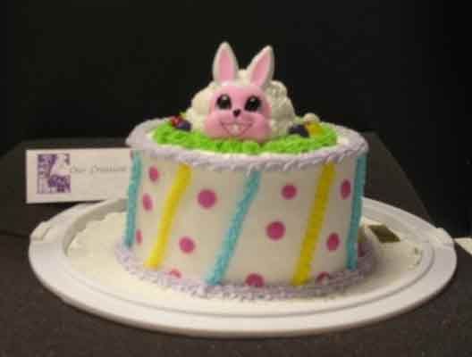 Easter cake with bunny topper, pastel frosting, polka dots, and grass detail.