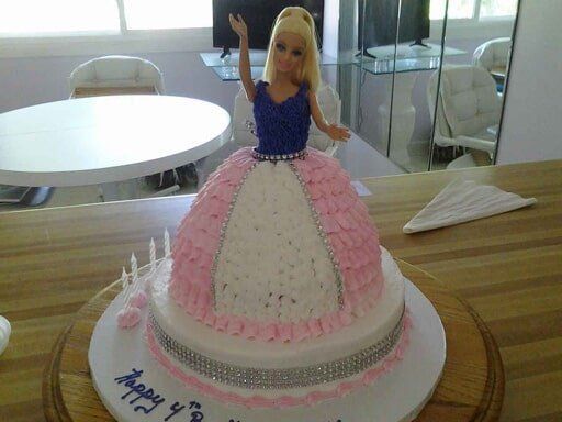 Barbie doll cake with pink and white frosting, candles, and 
