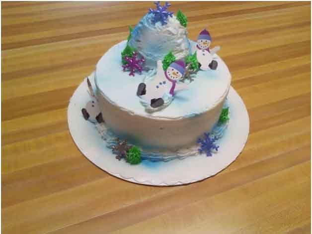 Snow-themed cake with snowmen, snowflakes, and an icy mountain peak.