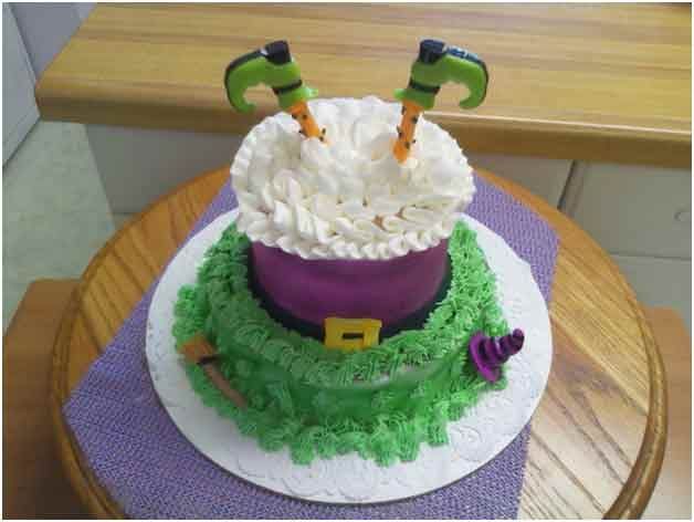 Witch-themed cupcake: purple bodice, green grass frosting, white cloud frosting, and green-legged witch feet.