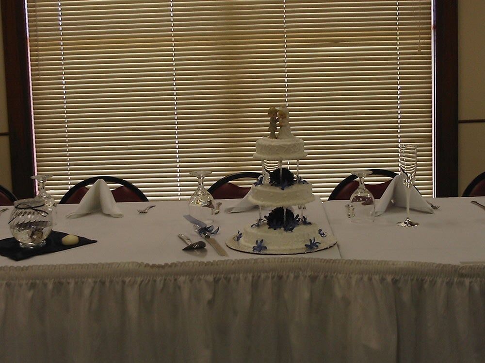 Wedding cake on a table set for a formal event, in front of a window.